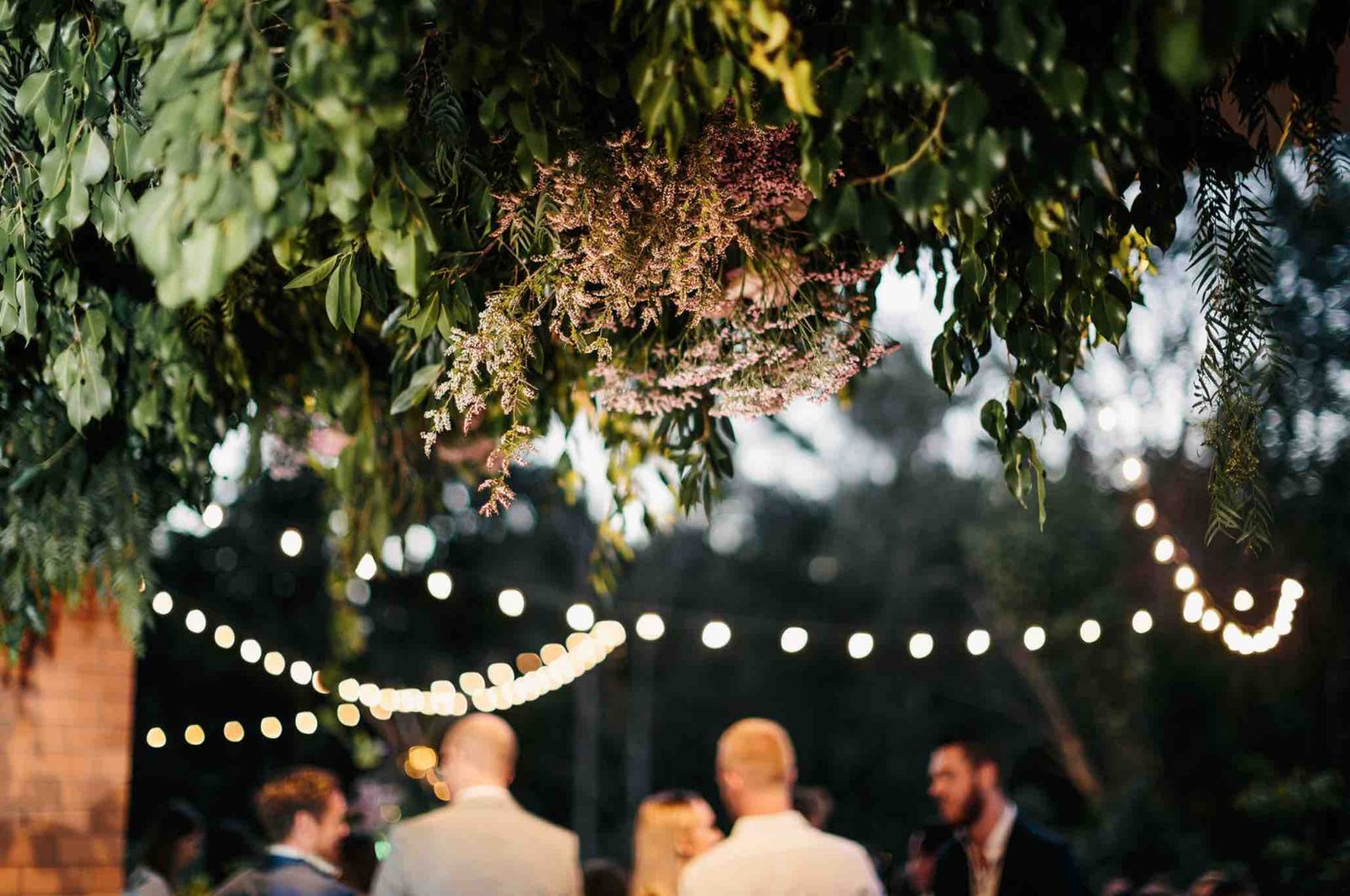 Festoon lights over guests in the Stable courtyard at dusk