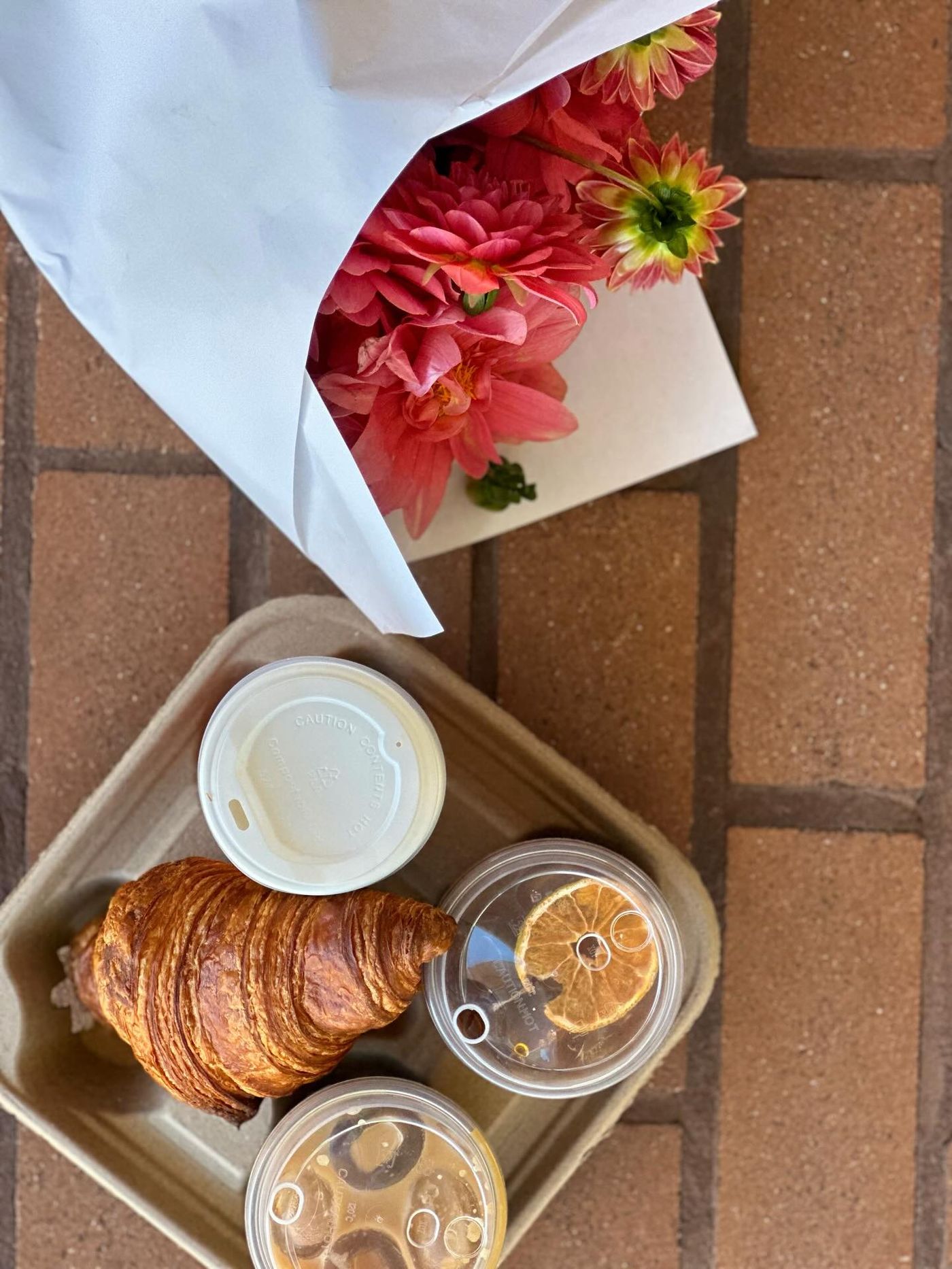 Croissant and takeaway coffees on brick