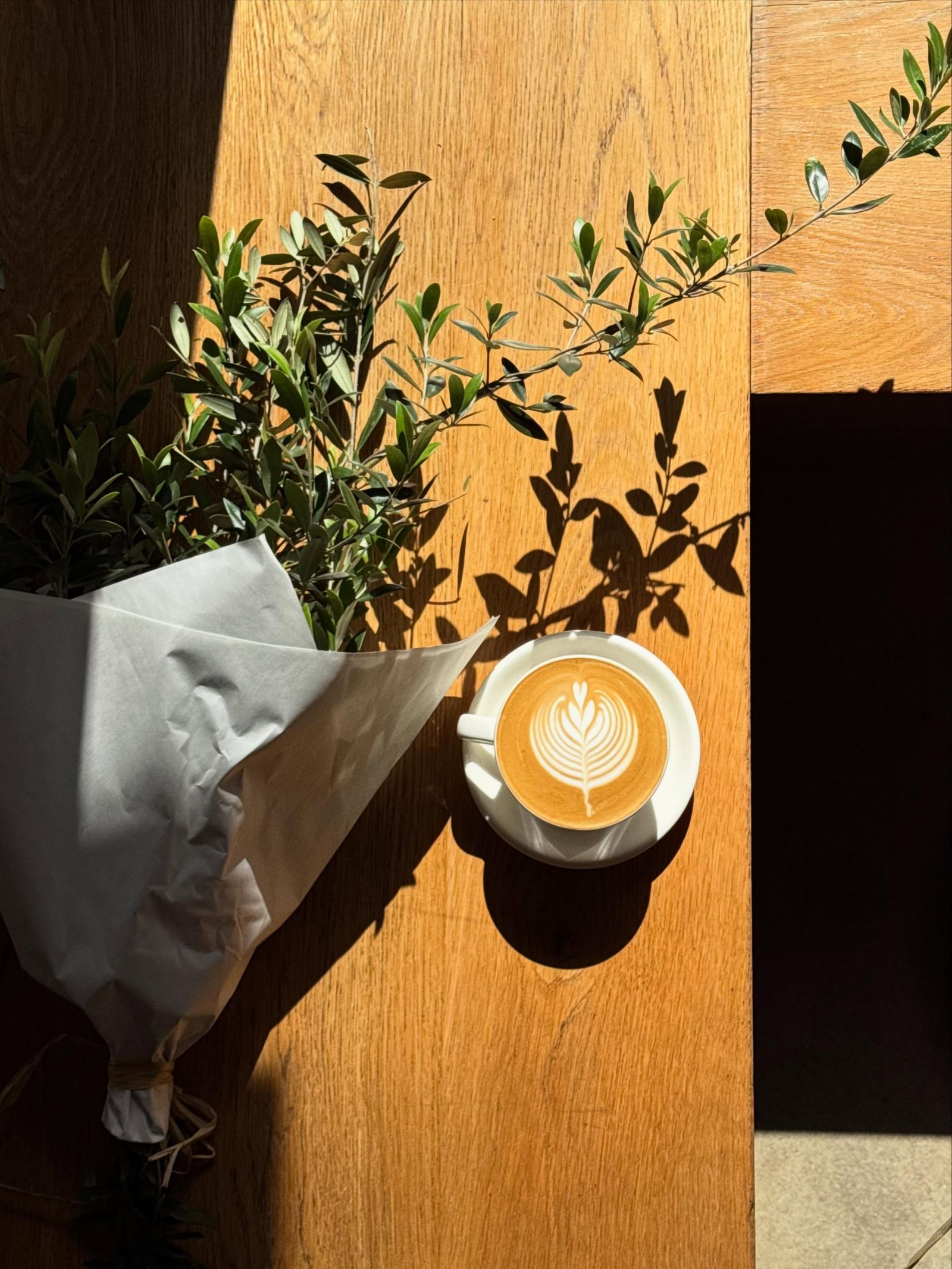 Latte in the morning sun on a timber bench at Stable