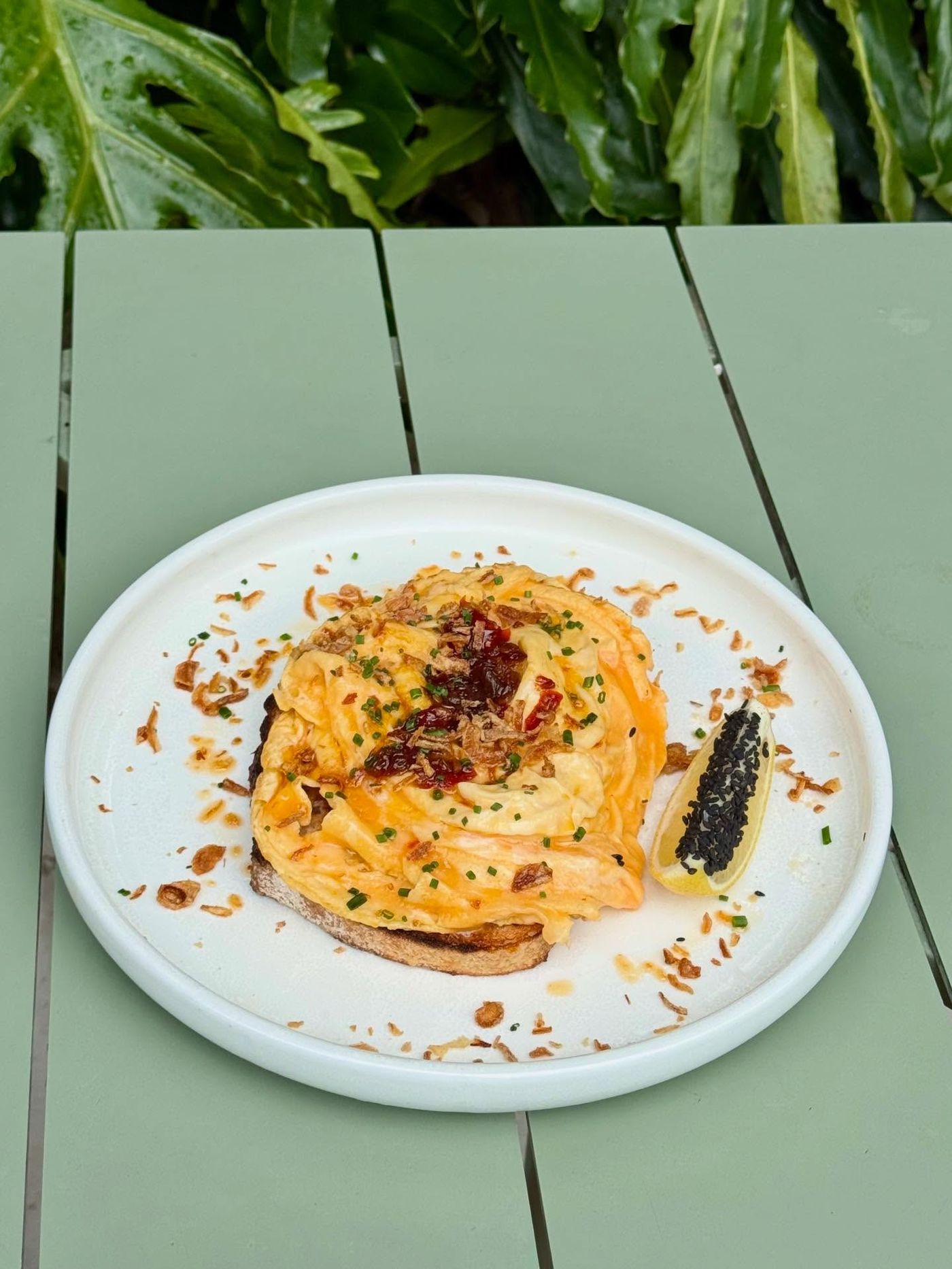 Plated eggs on toast on the green courtyard table